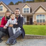 Happy Mixed Race Family in Front of Their Beautiful New Home.